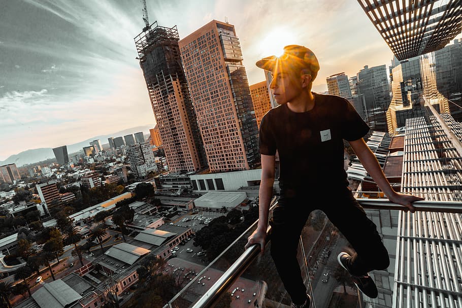 man sitting on rail of building, person, human, city, urban, town