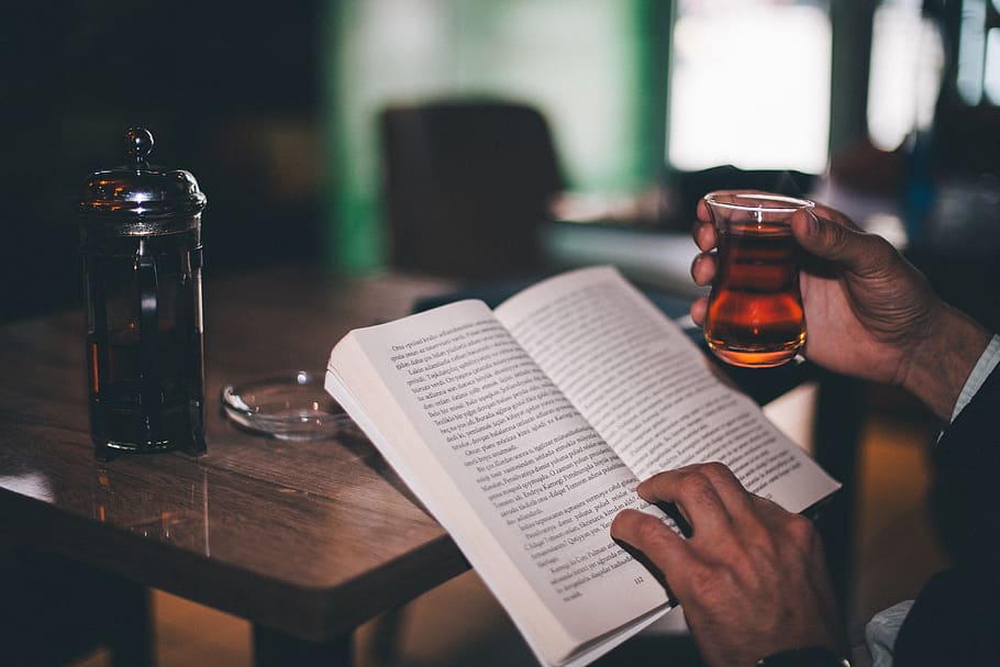 man reading book while holding glass, drink, food and drink, table HD wallpaper