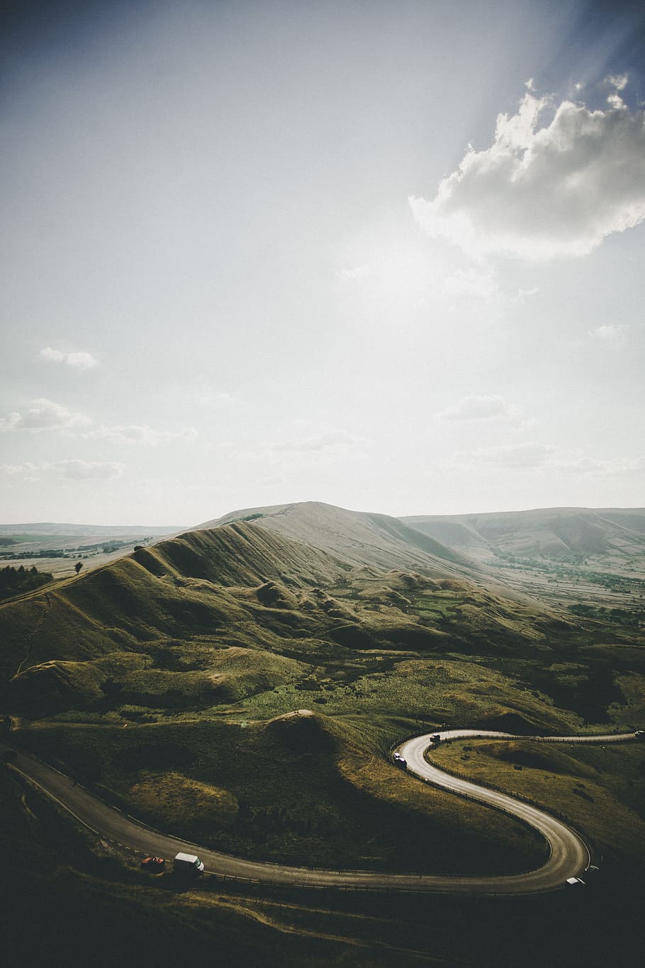 aerial photography of vehicle arriving on concrete road near mountains under white clouds at daytime HD wallpaper