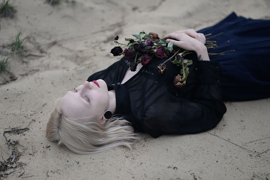 Woman Laying Holding Red Flowers, black dress, blond hair, close-up