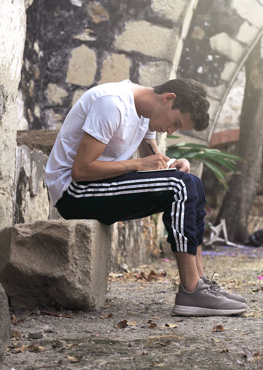 man sitting on stone writing down, one person, casual clothing HD wallpaper