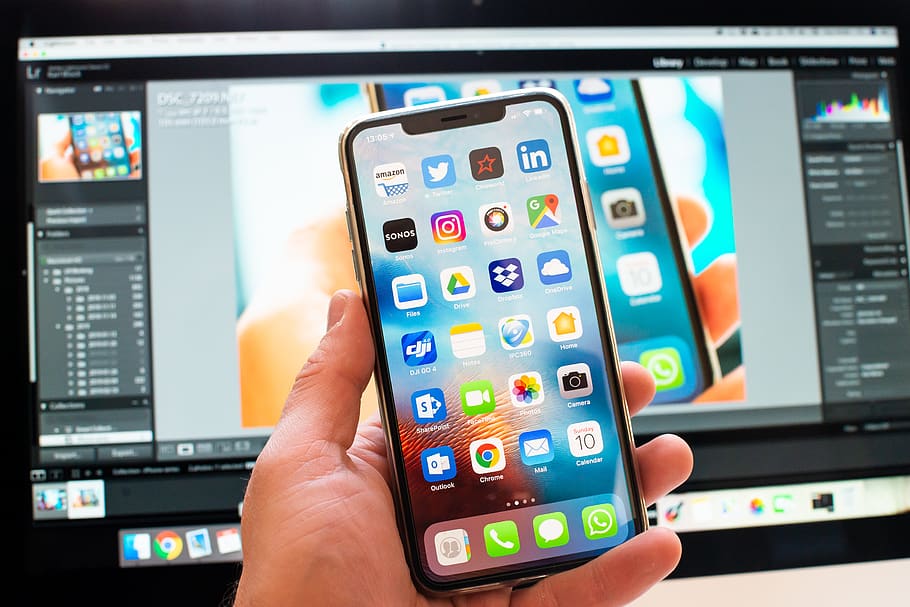 iPhone X held against computer monitor, cell phone, mobile phone