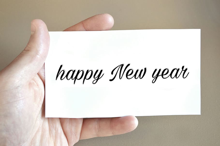 Hand holding a card that reads Happy New Year - white card in hand