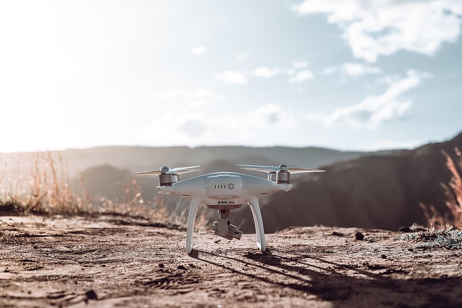 White Quadcopter Drone on Top of Brown Soil, clouds, daylight HD wallpaper