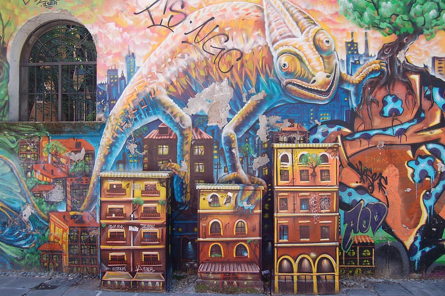 A wall mural of an oversized gecko climbing over tall city buildings.