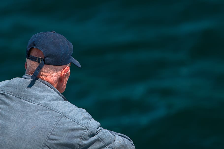 man looking on body of water wearing black cap, person, people