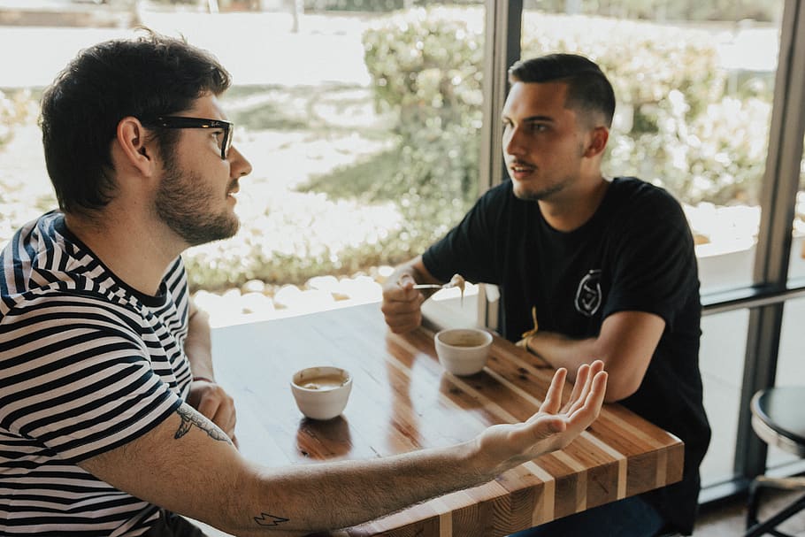 two men having conversation on table, human, person, coffee cup