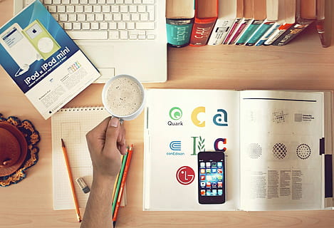 Overhead view of graphic design workstation with coffee, design tools and inspiration. HD wallpaper