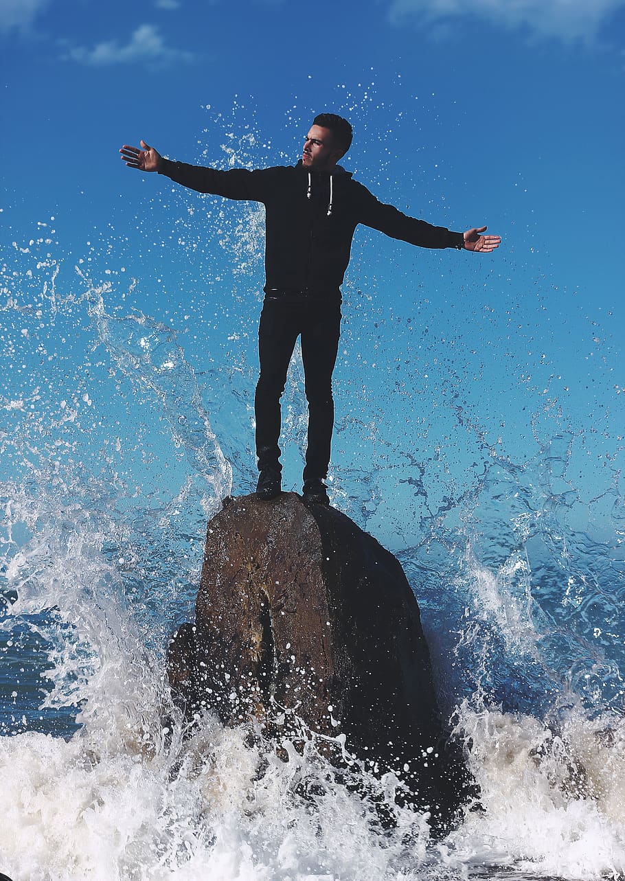 guy, man, wave, water, splash, rock, formation, beach, sea HD wallpaper