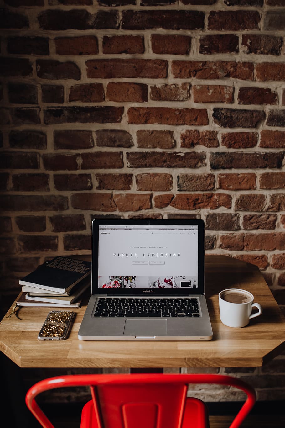 Creatives desk with laptop, camera, journals and books in front of brick wall, HD wallpaper