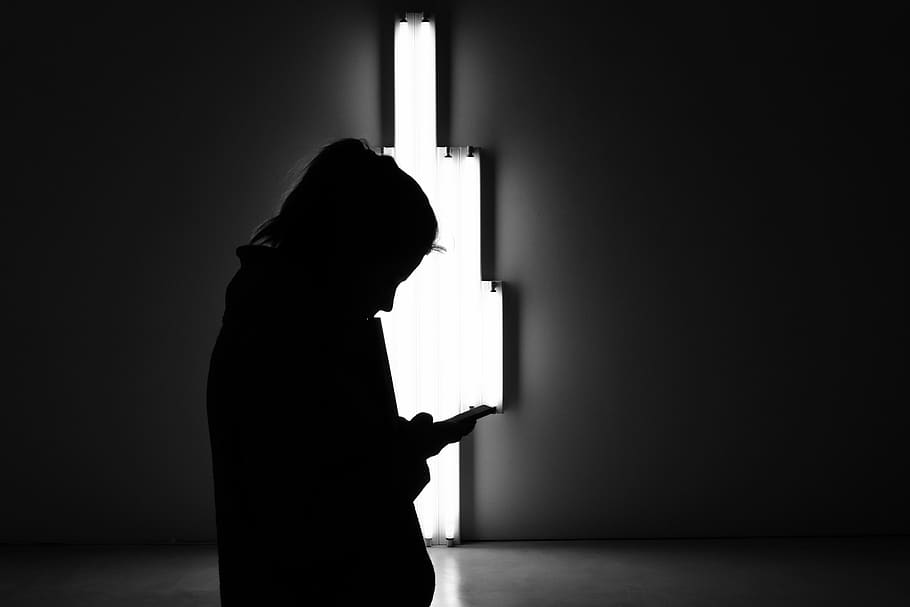 silhouette of person holding smartphone, indoors, one person