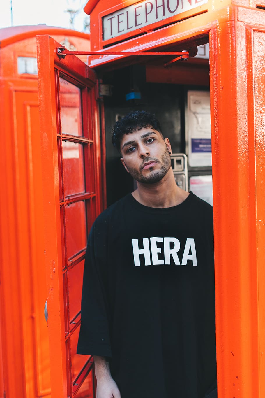 man standing inside telephone stall, looking at camera, one person HD wallpaper