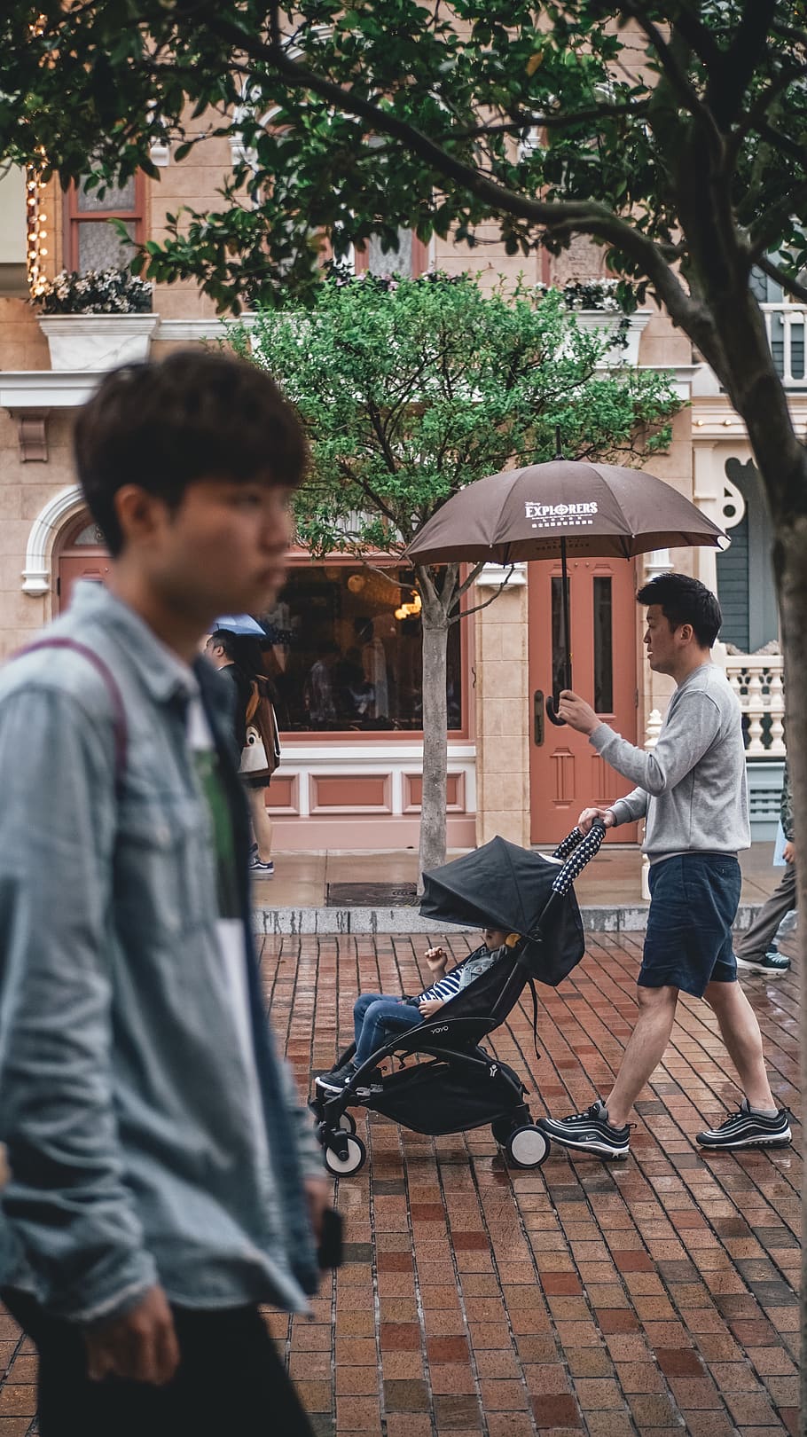 man holding umbrella while pushing stroller, men, real people HD wallpaper