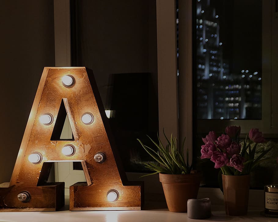 brown wooden A free standing letter near green leaf plant, indoor HD wallpaper