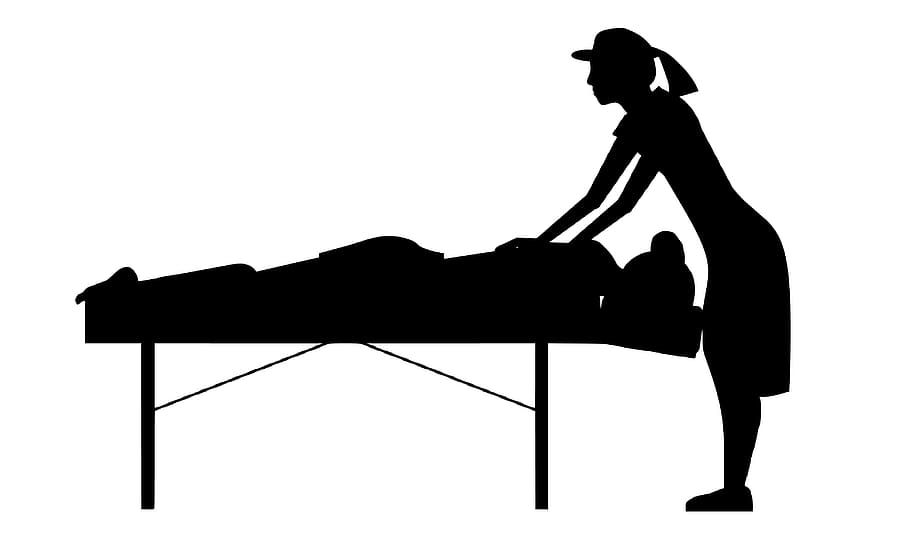 Massage therapist working on client on a massage table. Silhouette.