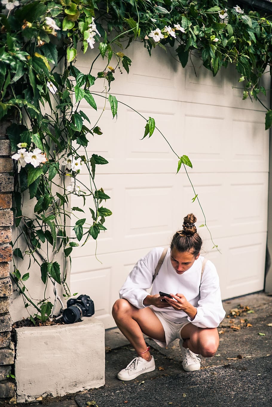Man Ducking Near White Garage Door While Holding Smartphone, camera HD wallpaper