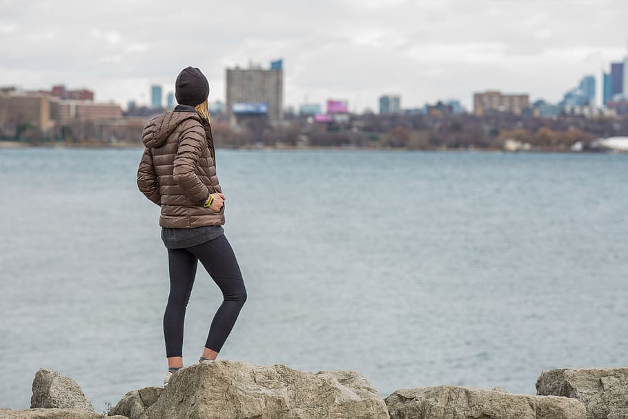 Man Wearing Brown Bubble Jacket Standing Near the Ocean, back view HD wallpaper