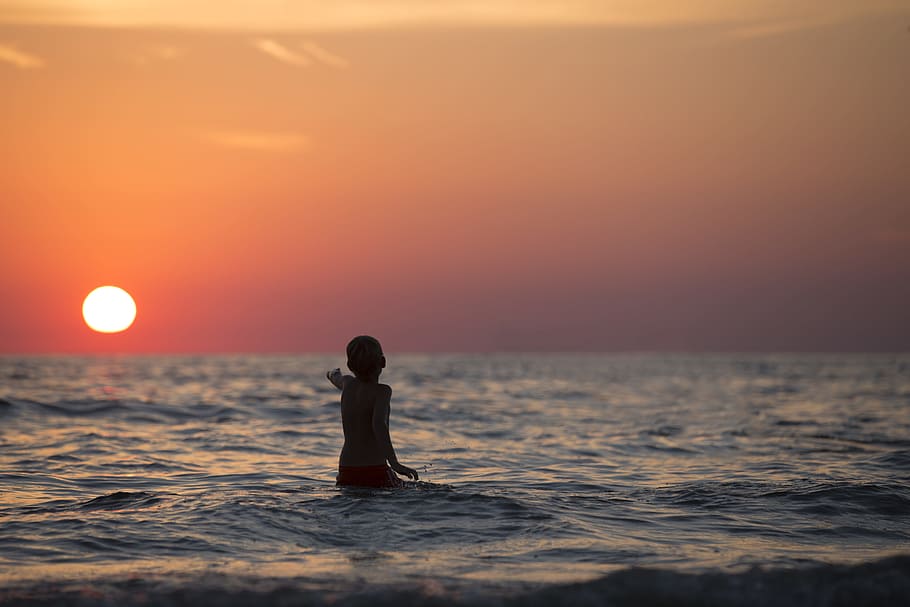 Boy in Ocean during Golden Hour, backlit, beach, care, dusk, evening HD wallpaper