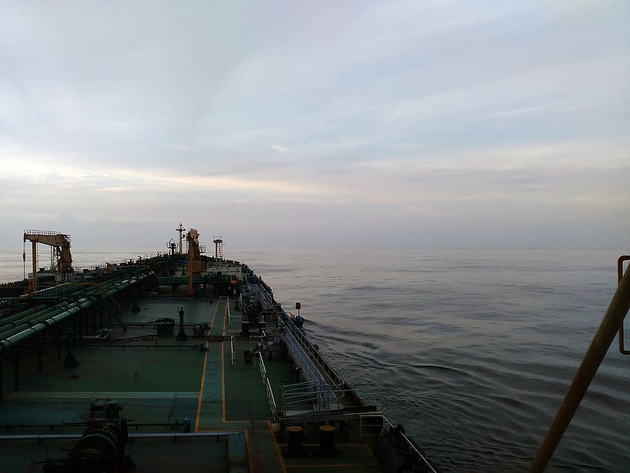 AN oil tanker ship sailing through calm sea. This photo is taken while going to Fujarah Dubai at an evening sunlight. The sky is light grayish blue in color.