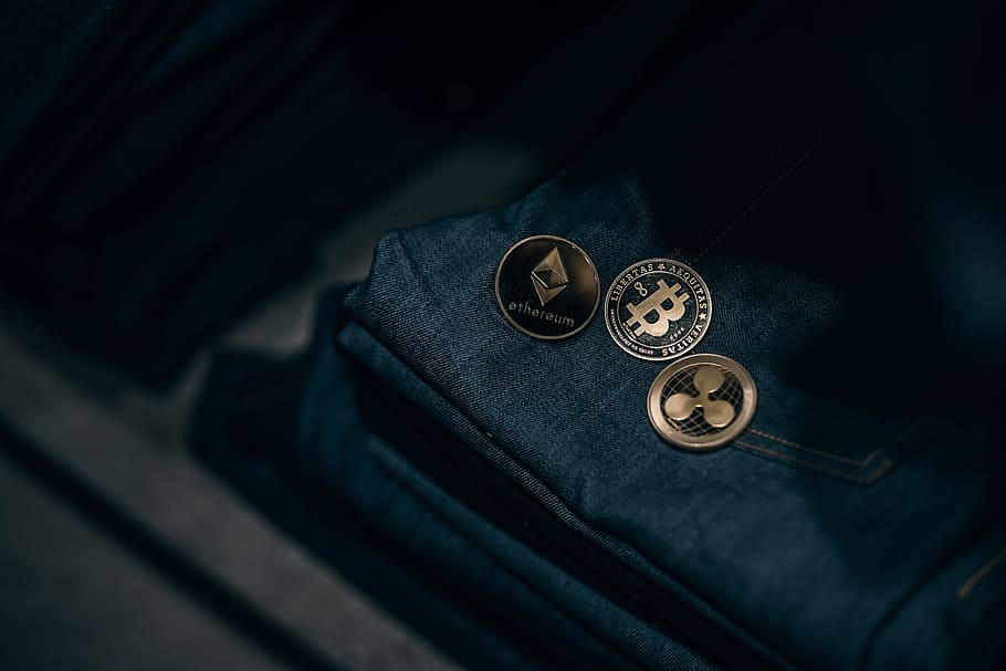 Golden Cryptocurrency Coins Laying on Top of Denim Jeans. Cryptocurrencies Accepted in Denim Store.