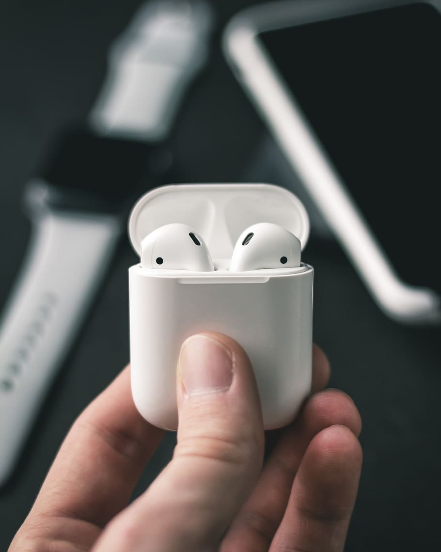 Apple AirPods with white charging case in selective focus photography