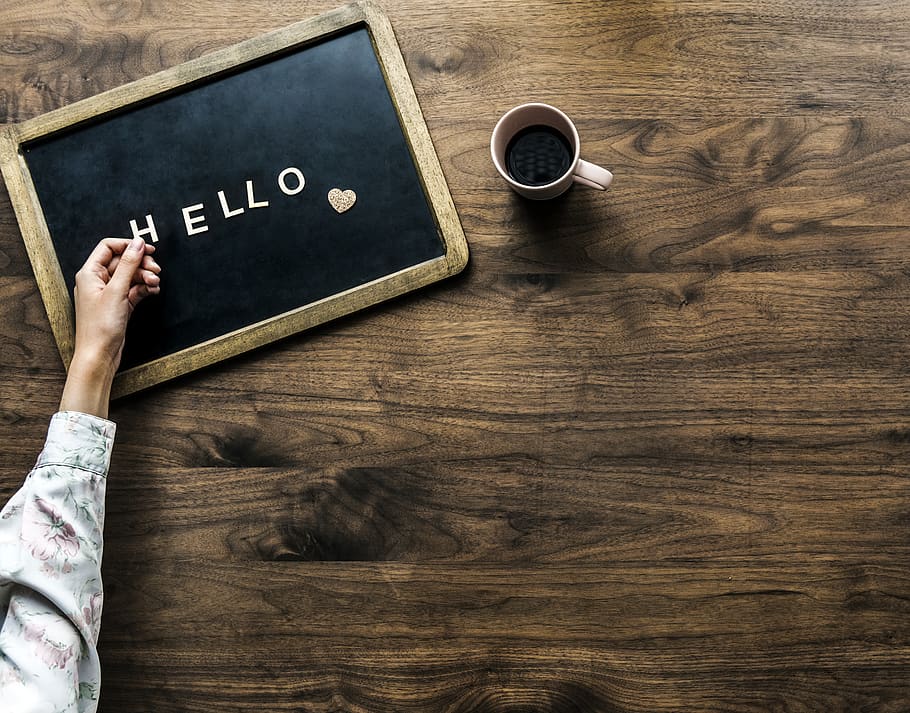 Person's Hand on Black Board With Hello Text Beside Brown Mug HD wallpaper
