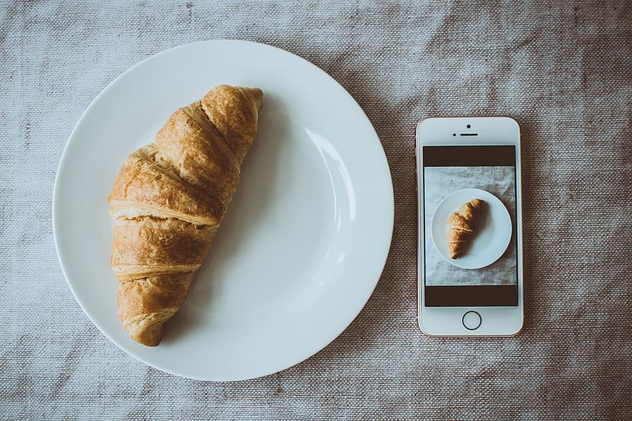 Croissant Bread on Round White Plate Beside Rose Gold Iphone Se Displaying Photo of Croissant Bread on Plate HD wallpaper