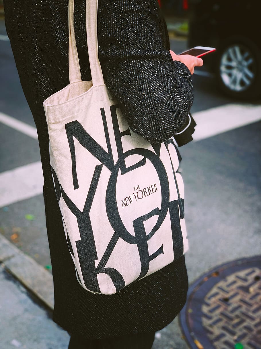 person carrying white and black tote bag, phone, new yorker, fashion