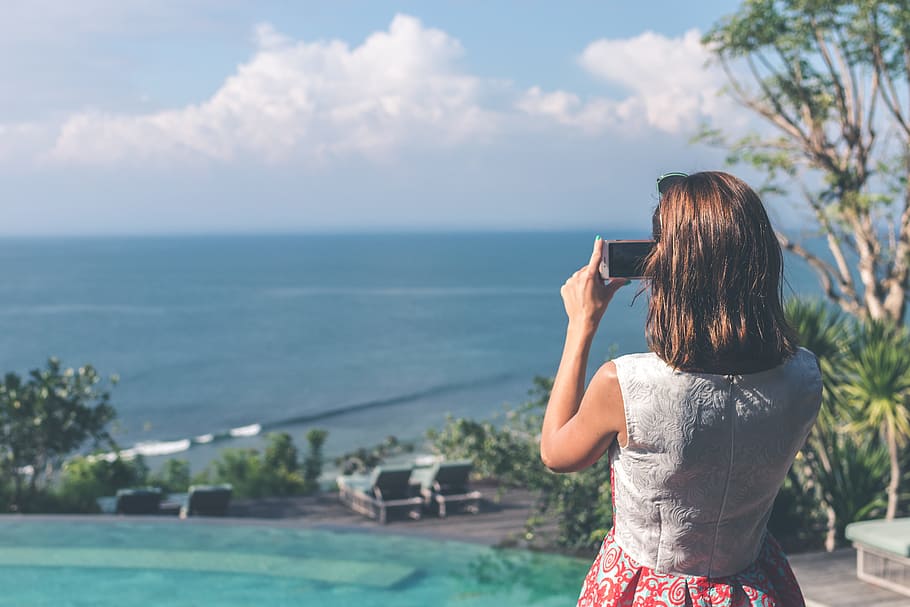Woman Wearing White and Red Sleeveless Dress Taking Photo of Beach HD wallpaper