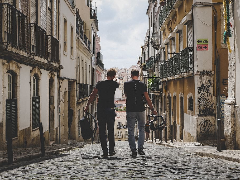 Two Man Walking in Between of Buildings Toward With Concrete Building HD wallpaper