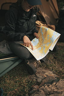 person wearing The North Face jacket sitting on sofa while holding map HD wallpaper