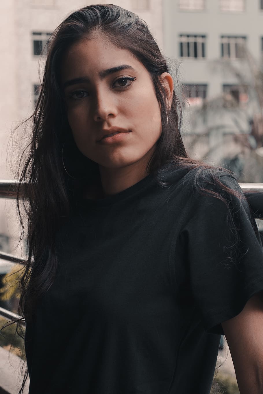 woman wearing black crew-neck shirt leaning on stainless steel rails