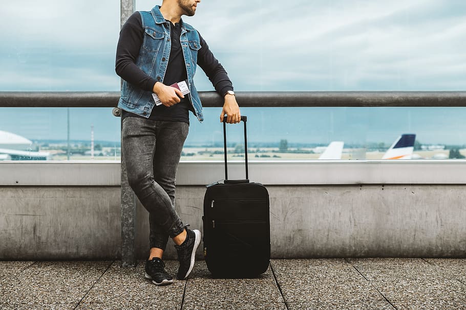 Calm male tourist is standing outdoor in airport and looking at airplanes. HD wallpaper