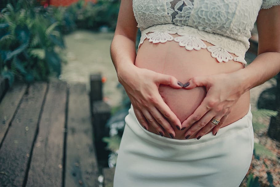 Pregnant Woman Wearing White Skirt Holding Her Tummy, baby bump