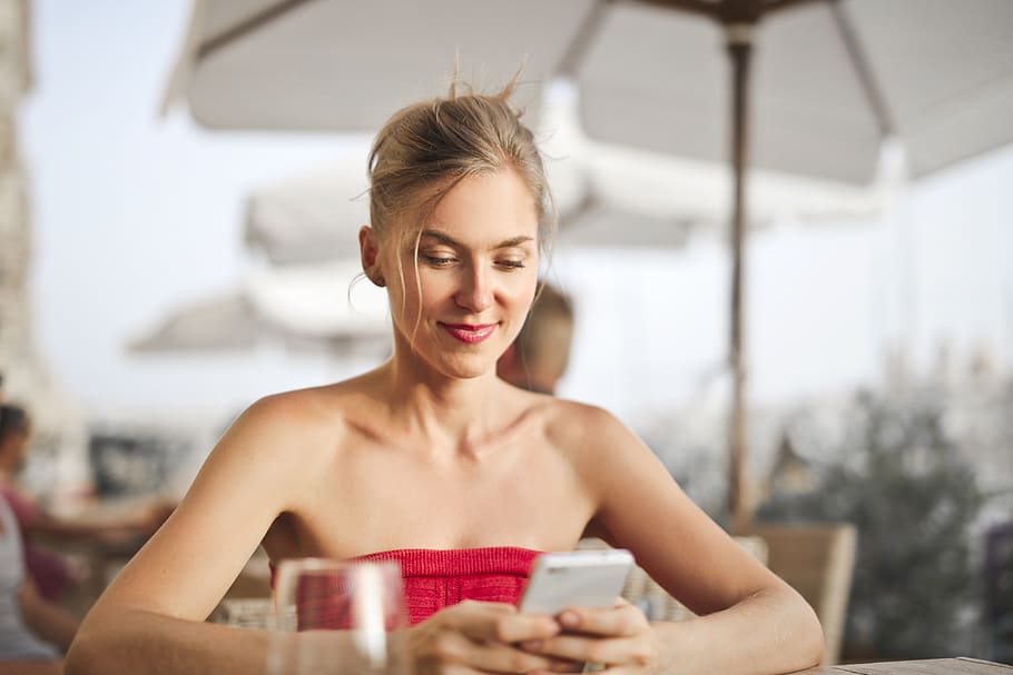 Woman Sitting on Chair While Holding Smartphone, blond, blonde