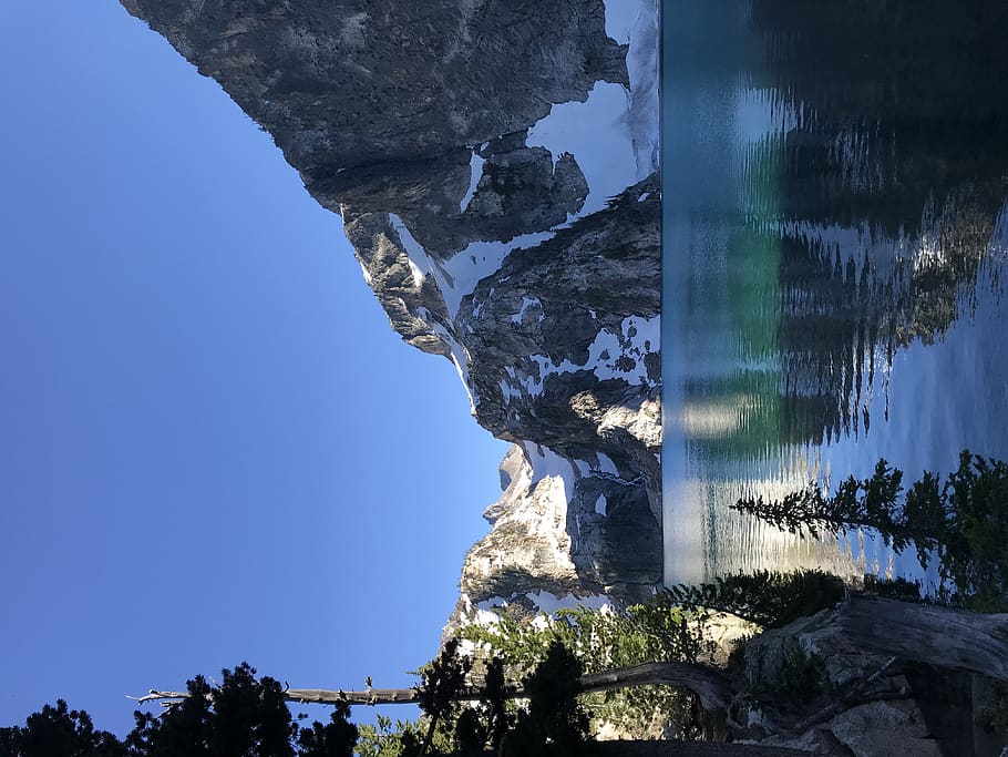 lake, sunlight, rocks, cliff, snow, trees, ice, blue, sky, clear sky HD wallpaper