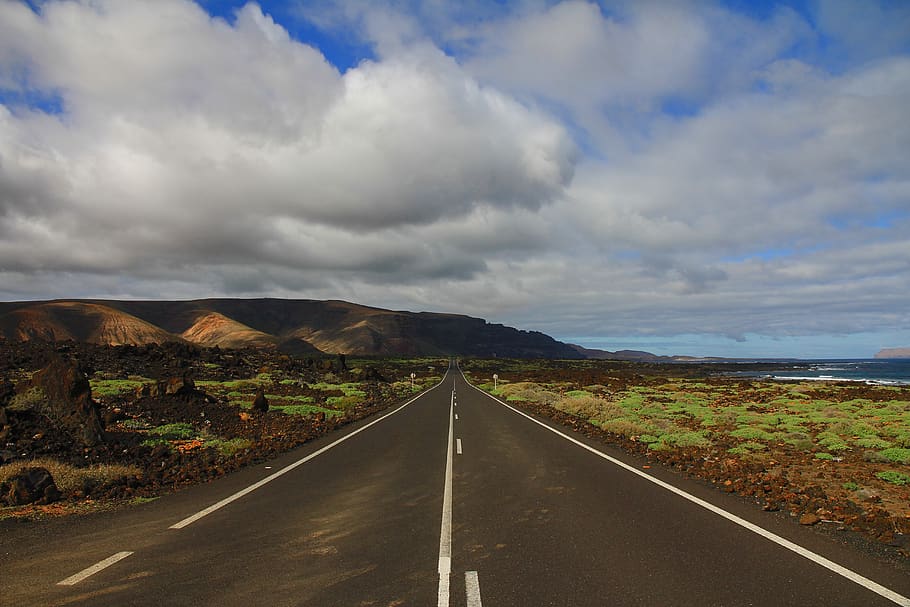 Concrete Road Between Mountain and Body of Water, asphalt, clouds HD wallpaper