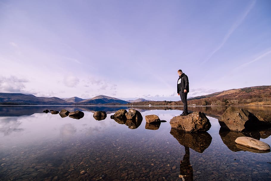 Person in Black Jacket Standing on Stone at Body of Water, adventure, HD wallpaper