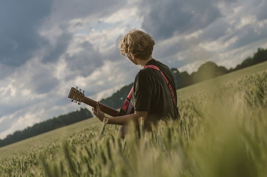 man paying guitar in the middle of green field during daytime, HD wallpaper