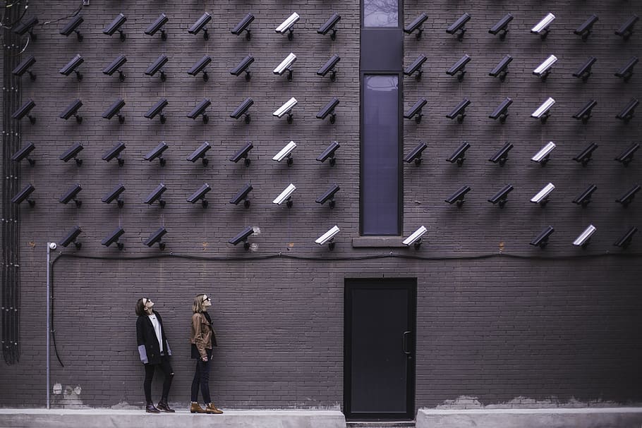 two-women-facing-security-camera-above-mounted-on-structure.jpg