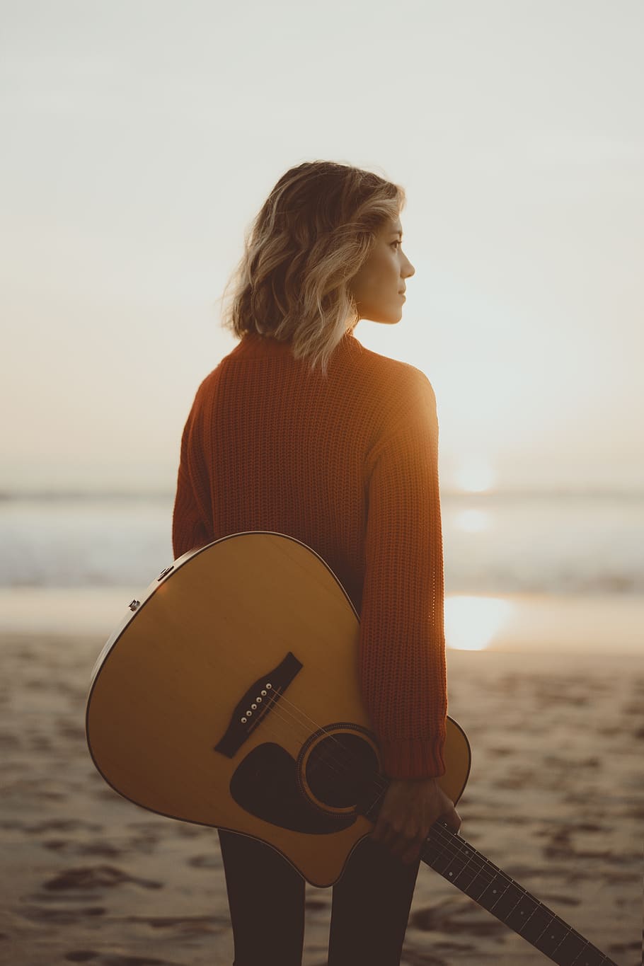 woman standing while holding acoustic guitar, sea, water, beach