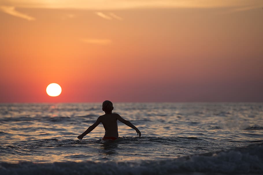 Silhouette Photo of Child on Body of Water during Golden Hour HD wallpaper
