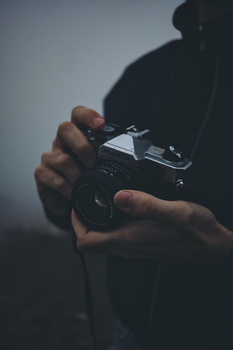 person holding black Fujica camera, electronics, finger, human