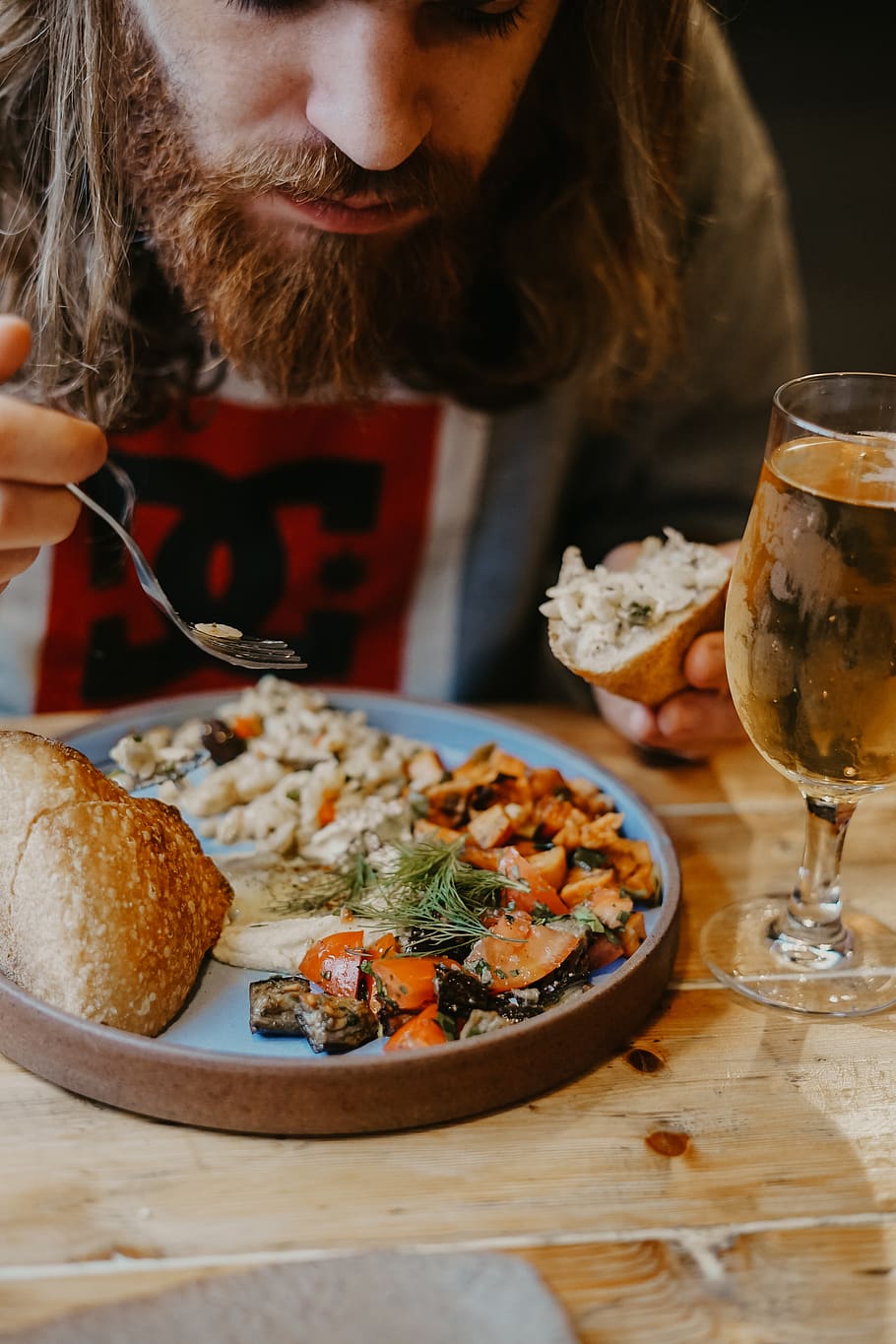 man eating bread and plate near filled wine glass, person, human
