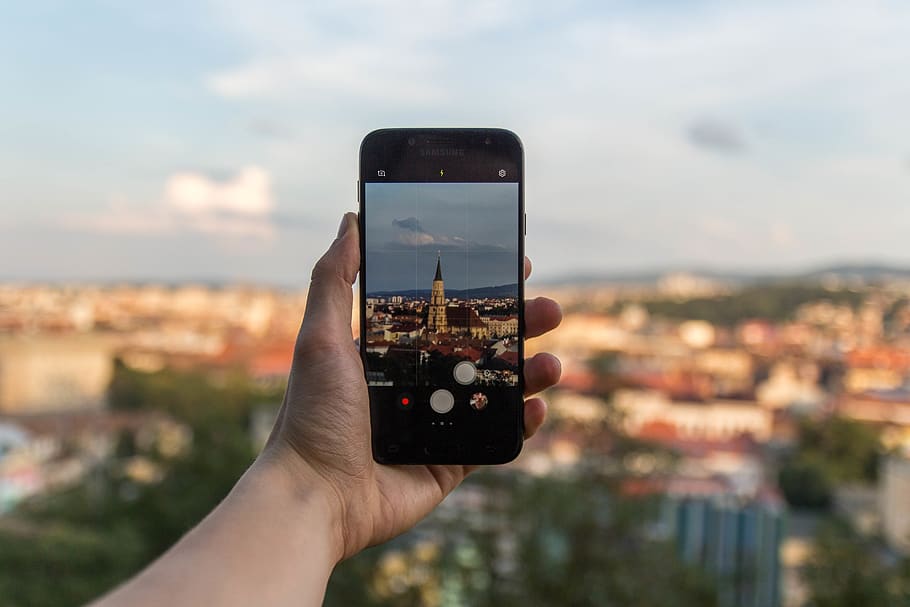 Person Taking Picture of Beige Building Using Black Smartphone HD wallpaper