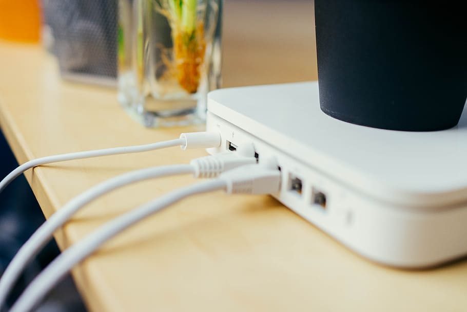 White Wireless Apple Router Connected with White Leads. Black Pot on Top of Router. Other Office Suppliers in Background., HD wallpaper