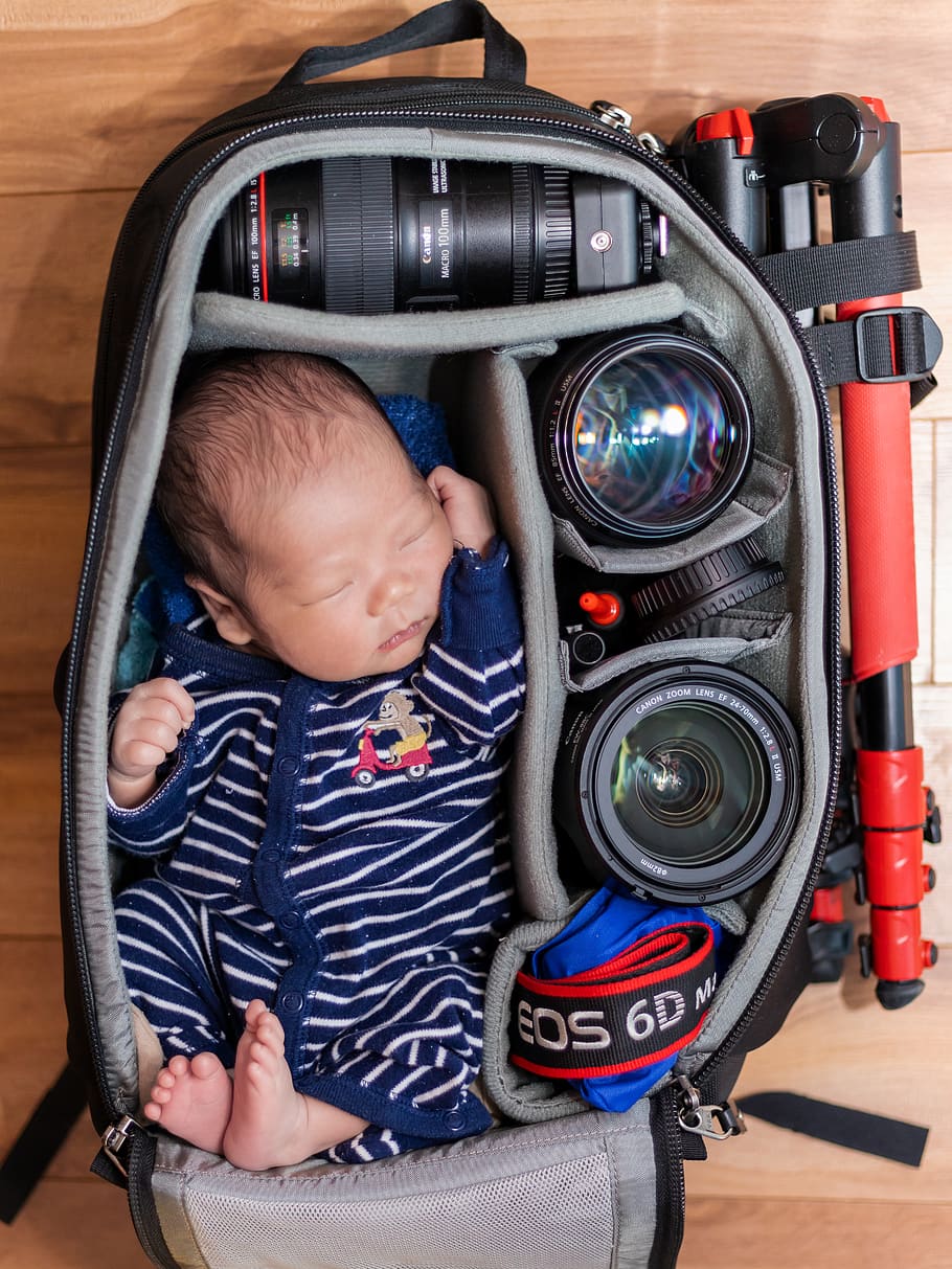 sleeping baby in a camera bag with camera lenses, child, young