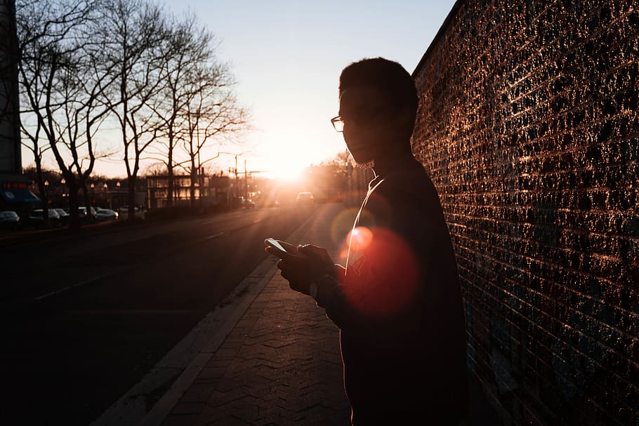 Boy Standing Near Wall Holding Smartphone While Looking Sideways HD wallpaper