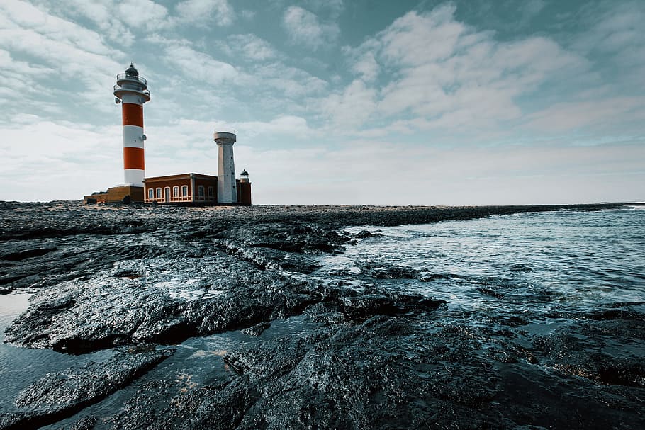 lighthouse, sea, day, ocean, water, sky, rocks, building, architecture HD wallpaper