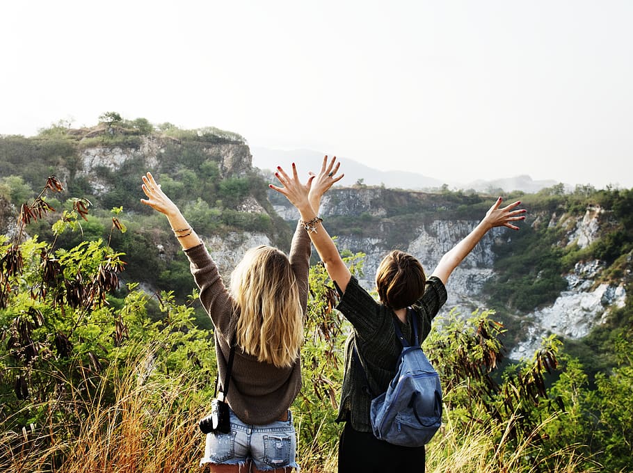 Two Girls on Two of a Mountain With Their Hands in the Air during Day HD wallpaper